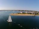 Leaving Nantucket: An aerial view of Thalia underway, with the town and Brant Point lighthouse, built in 1746.
